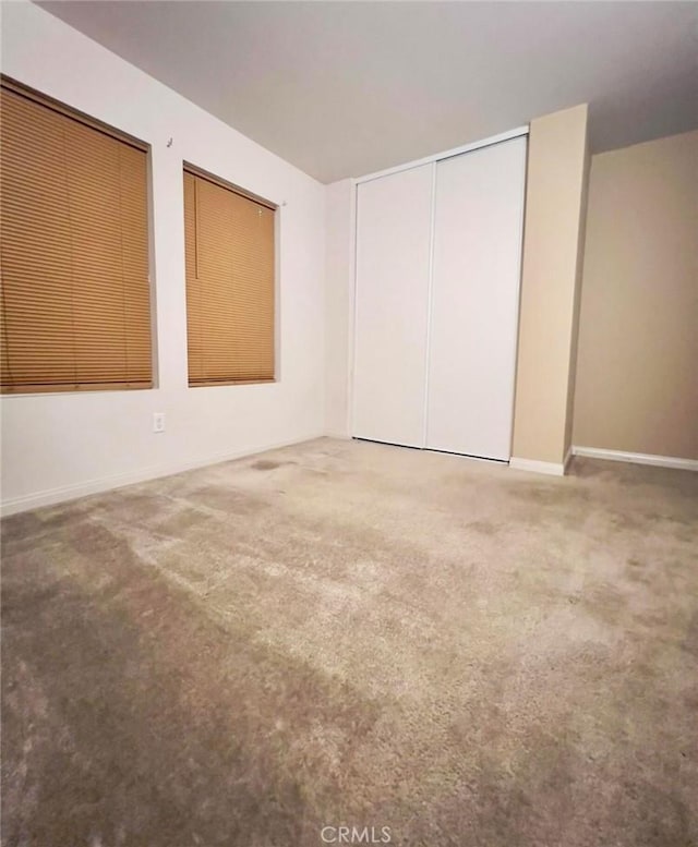 unfurnished bedroom featuring a closet, baseboards, and carpet flooring