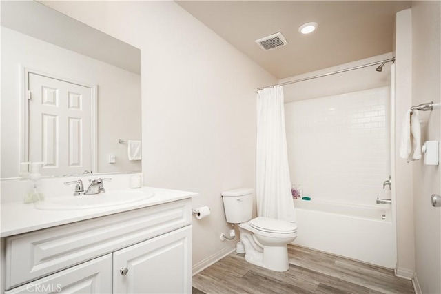 bathroom with toilet, wood finished floors, vanity, visible vents, and shower / tub combo with curtain