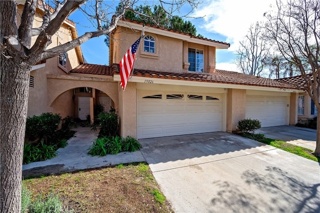 mediterranean / spanish home with concrete driveway, a tile roof, and stucco siding