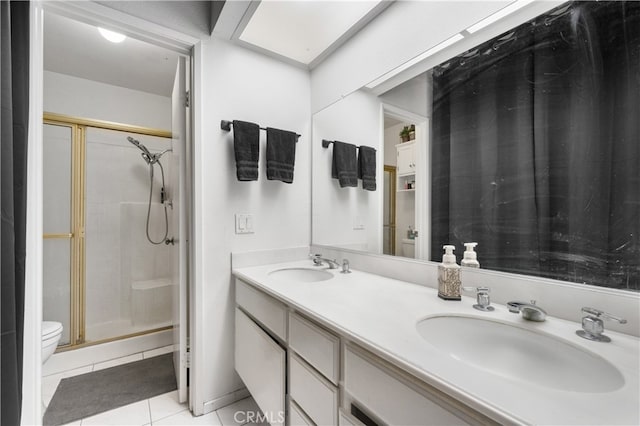 full bath with double vanity, a shower stall, a sink, and tile patterned floors