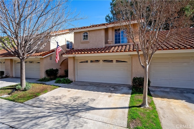 mediterranean / spanish house with a garage, concrete driveway, and stucco siding