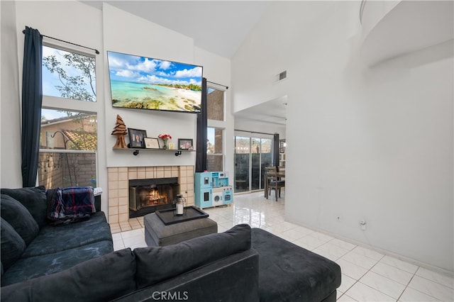 living room with light tile patterned floors, high vaulted ceiling, a tiled fireplace, and visible vents