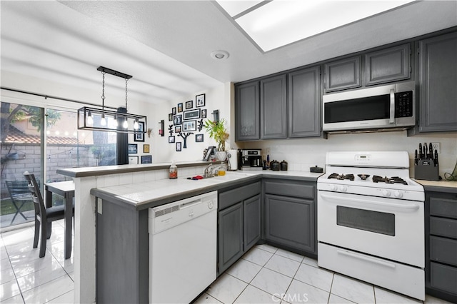 kitchen with gray cabinetry, a peninsula, white appliances, light countertops, and decorative light fixtures