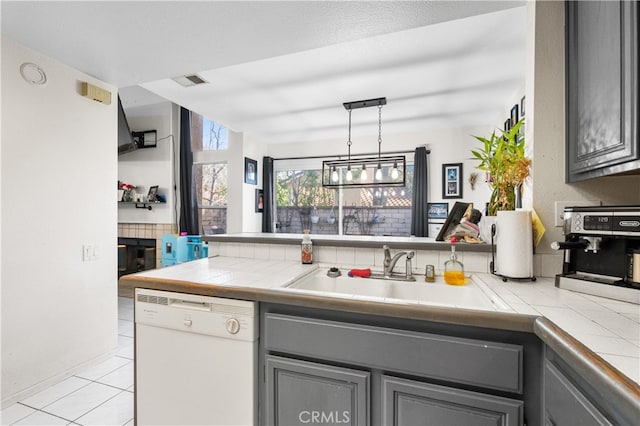 kitchen featuring dishwasher, tile countertops, hanging light fixtures, gray cabinetry, and a sink