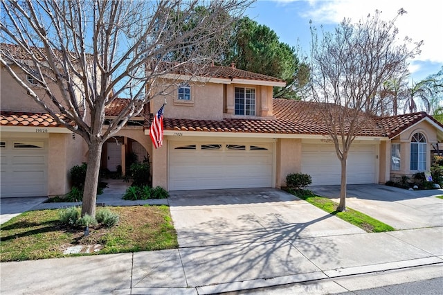 view of front of house with concrete driveway, a tiled roof, an attached garage, and stucco siding