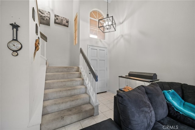 stairs featuring tile patterned flooring, a towering ceiling, and an inviting chandelier