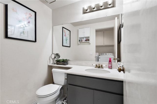 bathroom with toilet, independent washer and dryer, and vanity