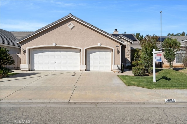 view of front of home featuring a garage, driveway, a tiled roof, and stucco siding