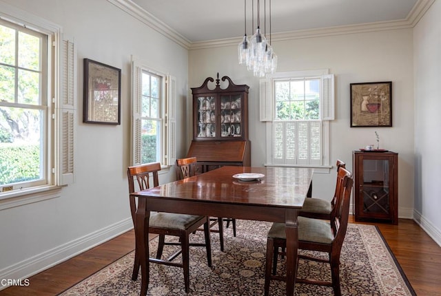 dining space featuring baseboards, ornamental molding, a chandelier, and wood finished floors