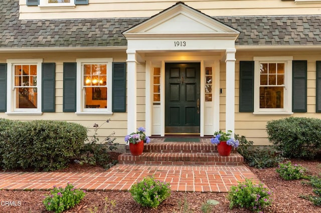 view of exterior entry with a shingled roof