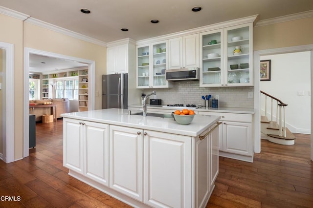 kitchen featuring white cabinets, an island with sink, glass insert cabinets, appliances with stainless steel finishes, and light countertops