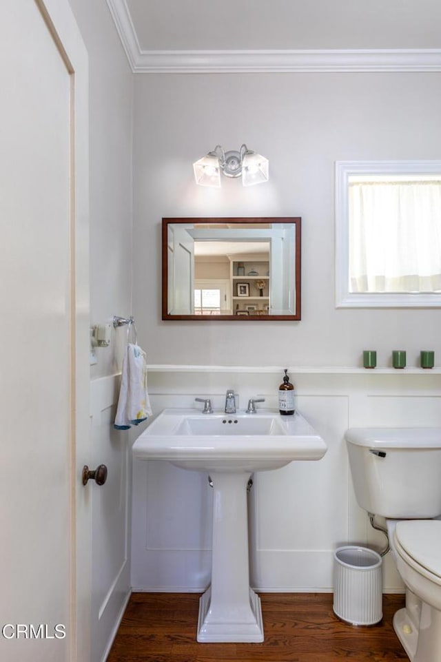 half bathroom featuring toilet, crown molding, and wood finished floors