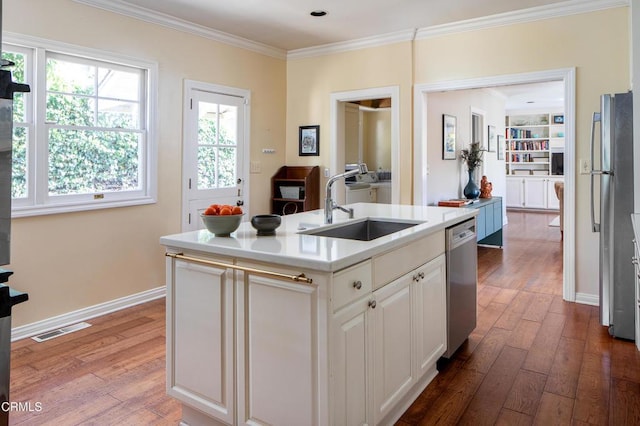 kitchen featuring white cabinets, an island with sink, appliances with stainless steel finishes, light countertops, and a sink