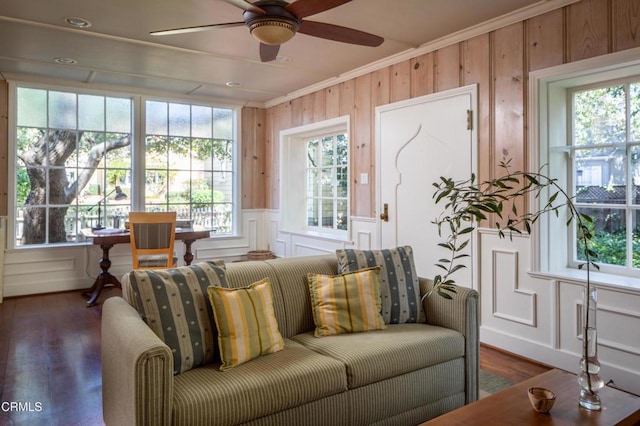 living room with ornamental molding, dark wood-style flooring, ceiling fan, and a decorative wall