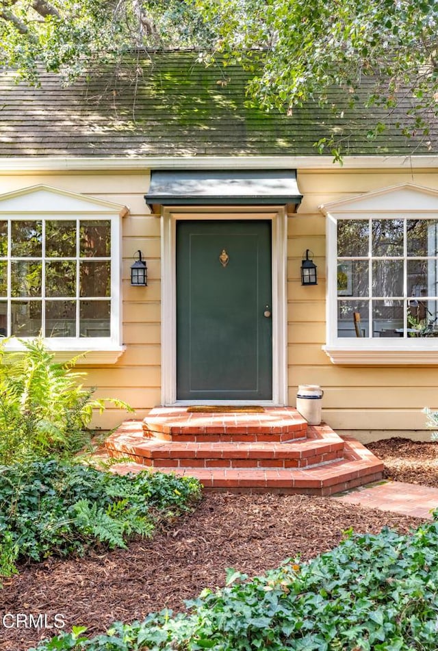 doorway to property with a shingled roof