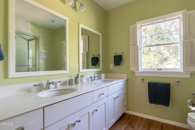 bathroom with double vanity, a sink, toilet, and baseboards