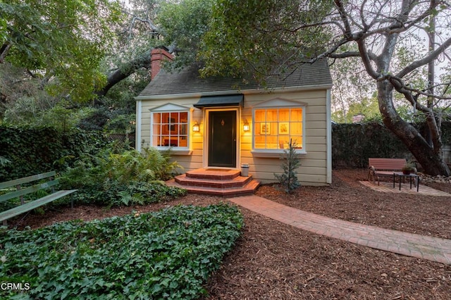 view of front of property with roof with shingles, fence, and a chimney