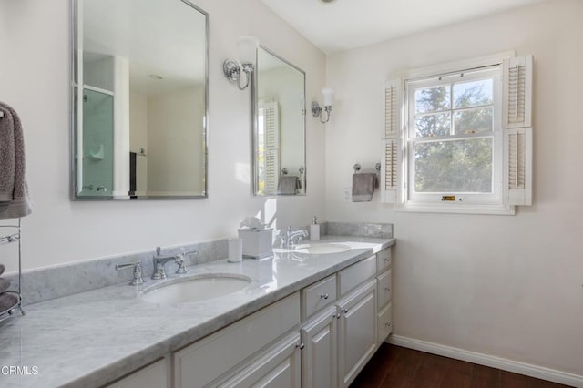 full bathroom with double vanity, baseboards, a sink, and wood finished floors