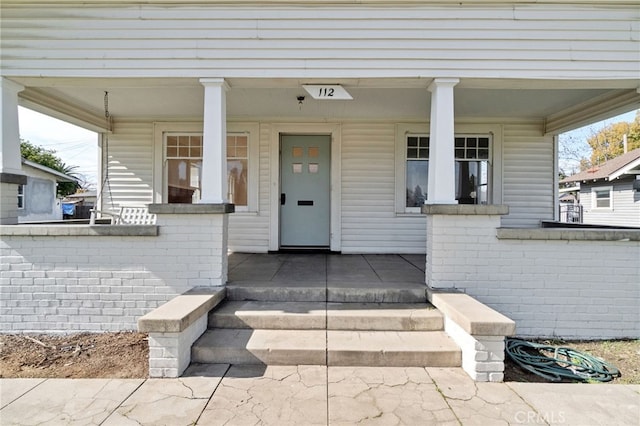 property entrance featuring brick siding and covered porch