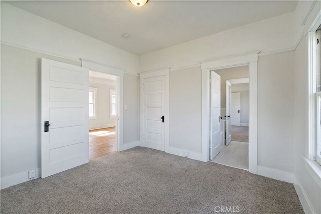 unfurnished bedroom with light colored carpet and baseboards