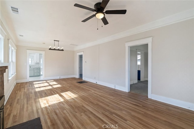 unfurnished living room featuring crown molding, plenty of natural light, baseboards, and light wood-type flooring