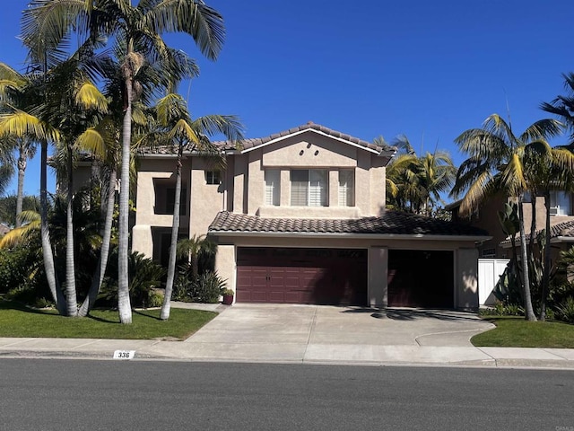 mediterranean / spanish-style house featuring a garage, fence, a tile roof, concrete driveway, and stucco siding