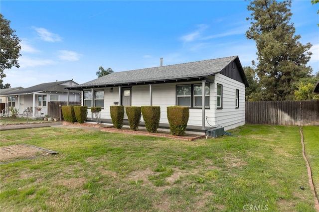 view of front of property with a front yard, fence, and roof with shingles