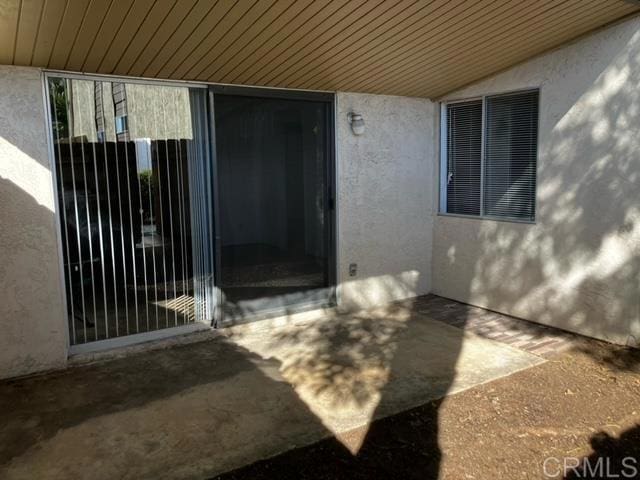 entrance to property featuring a patio and stucco siding