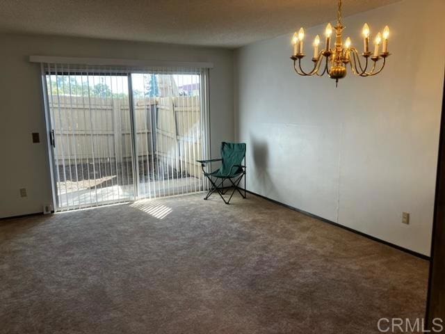 carpeted spare room featuring a notable chandelier