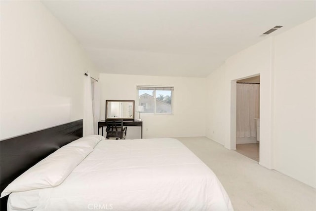 bedroom featuring carpet, visible vents, vaulted ceiling, and ensuite bathroom