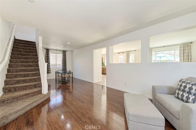 living area with plenty of natural light, dark wood finished floors, baseboards, and stairs