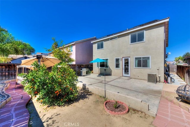 back of property with a fenced backyard, central AC, a patio, and stucco siding