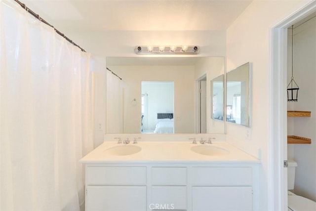 ensuite bathroom featuring connected bathroom, a sink, toilet, and double vanity