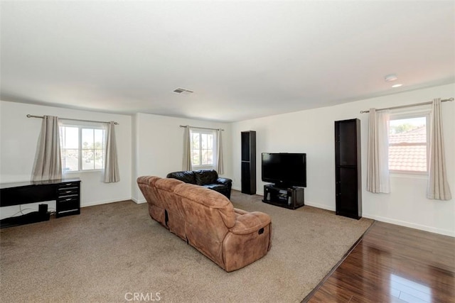 living room with a healthy amount of sunlight, visible vents, baseboards, and wood finished floors