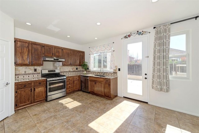 kitchen with tasteful backsplash, light countertops, appliances with stainless steel finishes, a sink, and under cabinet range hood