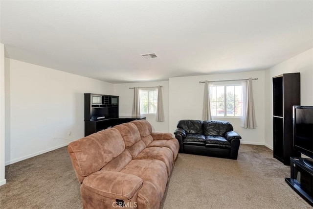 carpeted living area featuring plenty of natural light, visible vents, and baseboards