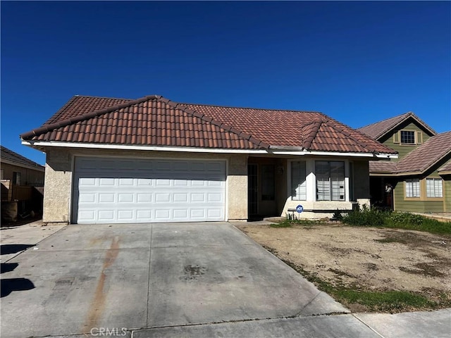 view of front of house featuring a garage, concrete driveway, a tile roof, and stucco siding