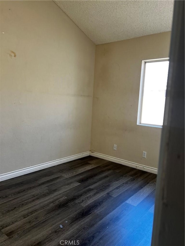 empty room featuring dark wood-style floors, baseboards, and a textured ceiling