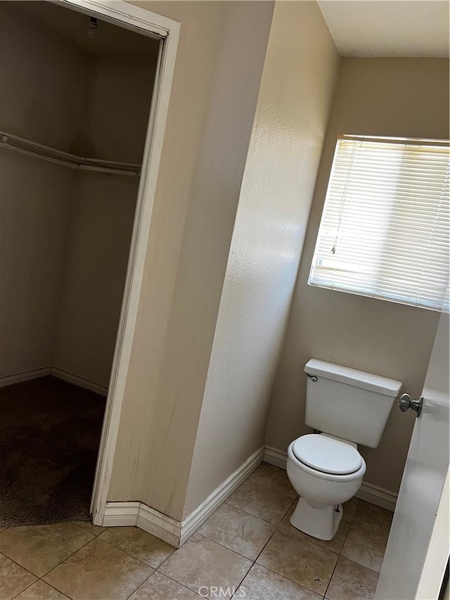 bathroom with toilet, baseboards, and tile patterned floors