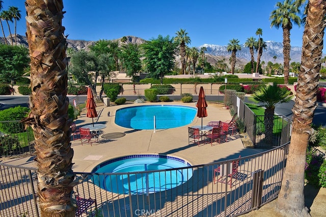 community pool with fence, a mountain view, a community hot tub, and a patio