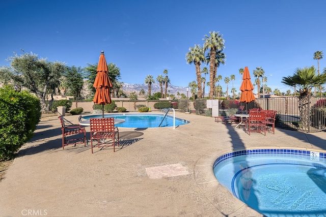 pool featuring a patio area, fence, a mountain view, and a community hot tub