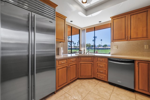 kitchen with dishwashing machine, stainless steel built in refrigerator, light tile patterned flooring, and light countertops