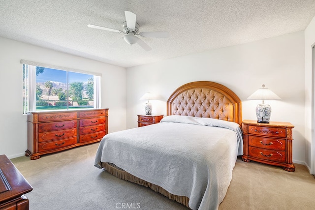 bedroom featuring light carpet, ceiling fan, a textured ceiling, and baseboards