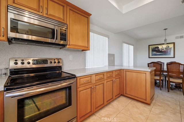 kitchen featuring visible vents, hanging light fixtures, appliances with stainless steel finishes, brown cabinetry, and a peninsula