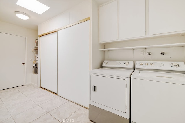 washroom with light tile patterned floors, washing machine and dryer, cabinet space, and a skylight