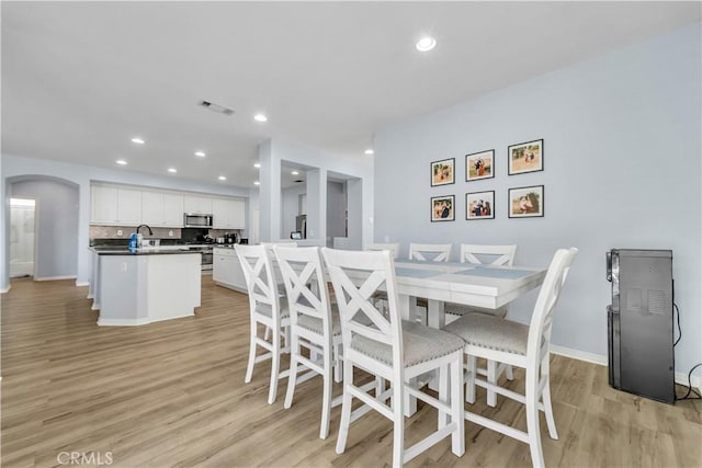 dining space with arched walkways, recessed lighting, visible vents, baseboards, and light wood-type flooring