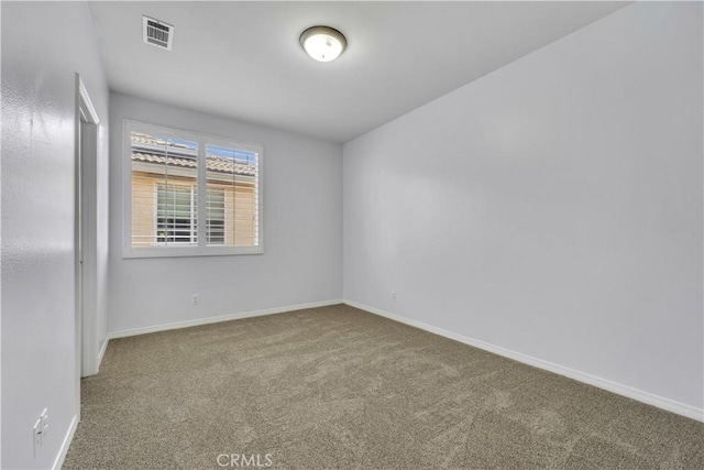 unfurnished room with carpet, visible vents, and baseboards