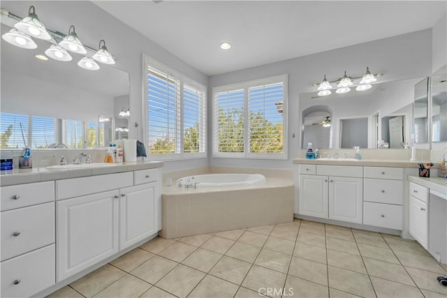 full bath featuring a ceiling fan, two vanities, a sink, tile patterned flooring, and a bath