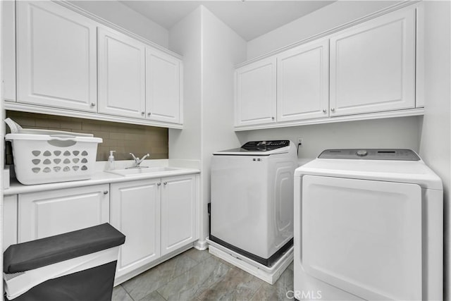 clothes washing area featuring cabinet space, separate washer and dryer, and a sink