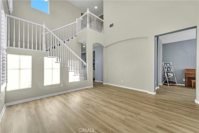 unfurnished living room featuring stairs, a wealth of natural light, visible vents, and wood finished floors